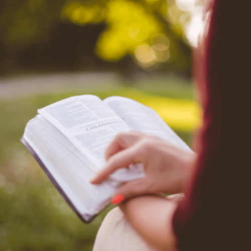 Woman holding open Bible on her lap outside